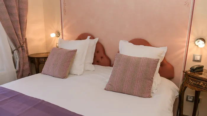 Lit douillet avec oreillers et couverture violette à l'Hôtel Villa Aultia