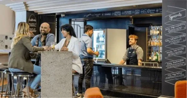 People sitting near a bar in an event space at a Grand Chancellor Hotel