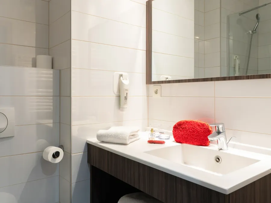 Clean bathroom with toiletries and a red cosmetic bag in Superior Studio at Appart’Hôtel Hévéa in Valence.