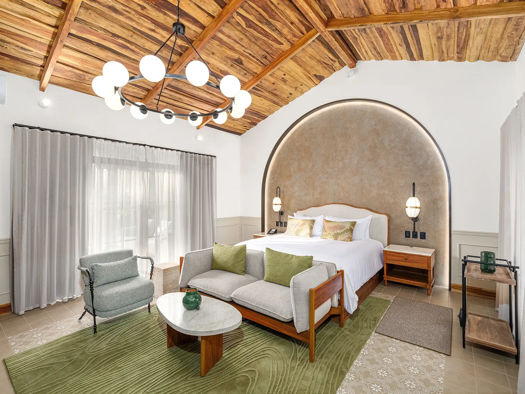 Suite presidencial con sofá y cama junto a una pared texturizada, con vistas a la exuberante selva en la Hacienda de la Selva de Santa Lucía