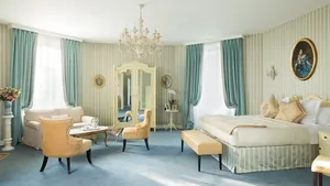 Chambre élégante avec lit, mobilier et lustre au Château Laroche Ploquin