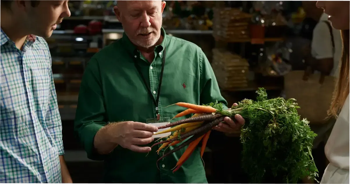 A man holding some carrots at the Adelaide Central Market.