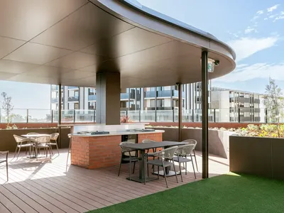 Outdoor rooftop lounge area with wooden flooring, green turf, and modern furniture at Caulfield Place.