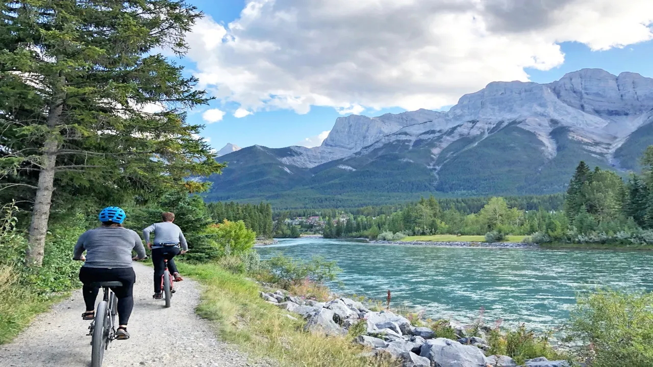 Two people bike along a trail near the river outside of Canmore.