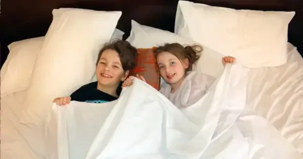 Two children smiling in bed at Hotel Grand Chancellor Adelaide