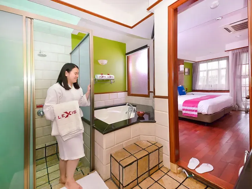 Woman in spa robe in glass shower of deluxe water chalet bathroom connected to a bedroom – Lexis Port Dickson