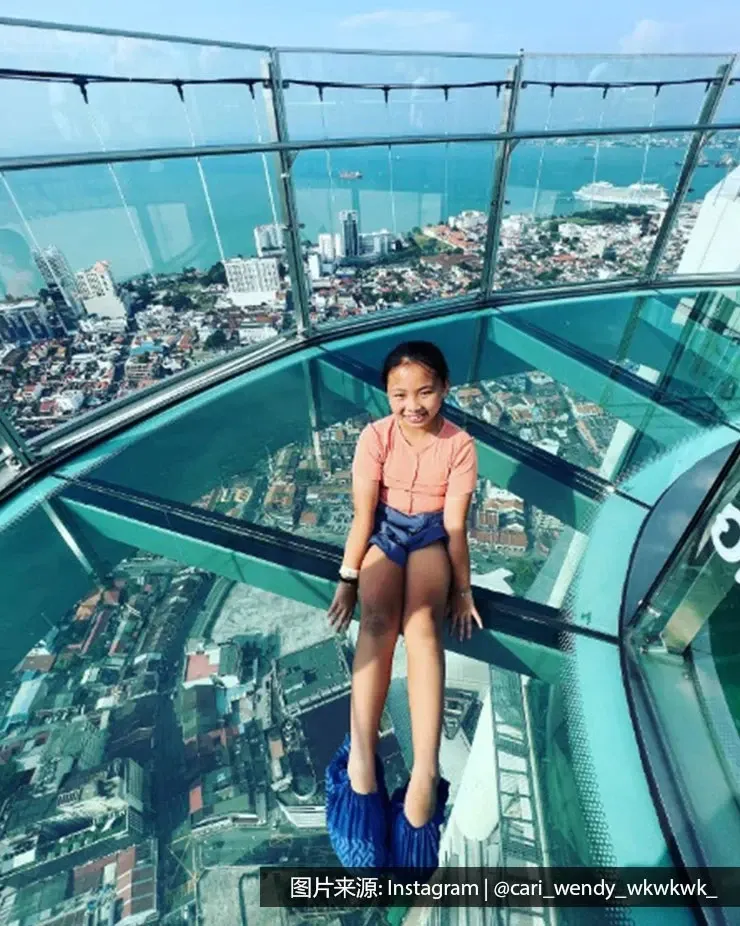 一名女孩坐在The TOP槟城彩虹天空步道的地上 - 槟城丽昇豪华酒店