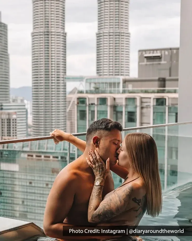 A couple shares a kiss with KLCC skyline in the background, capturing a romantic staycation moment together.