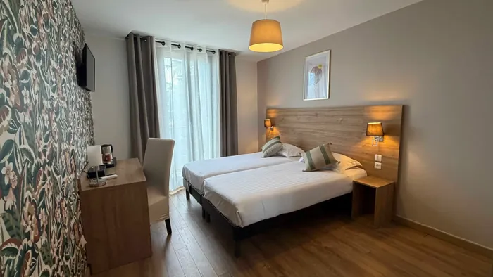 Chambre élégante avec deux lits jumeaux et un bureau au Grand Hôtel Molière.