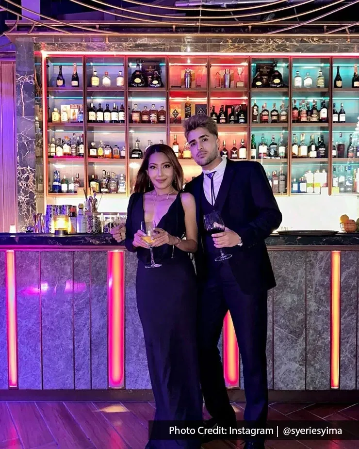 A couple posing together at a bar during a romantic night out.