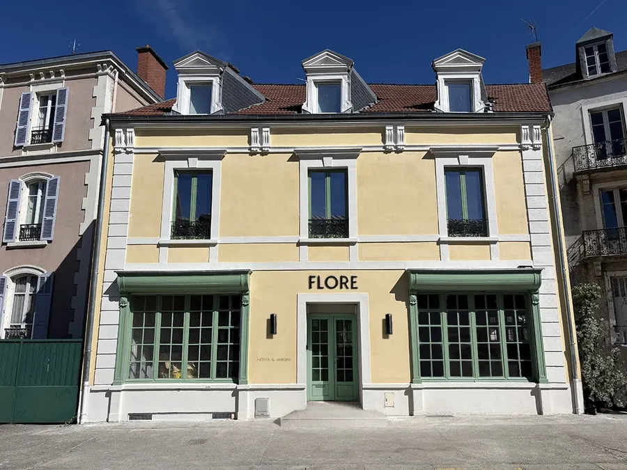 Façade jaune et verte avec fenêtres à lucarnes et enseigne Flore au Flore Hôtel & Jardin