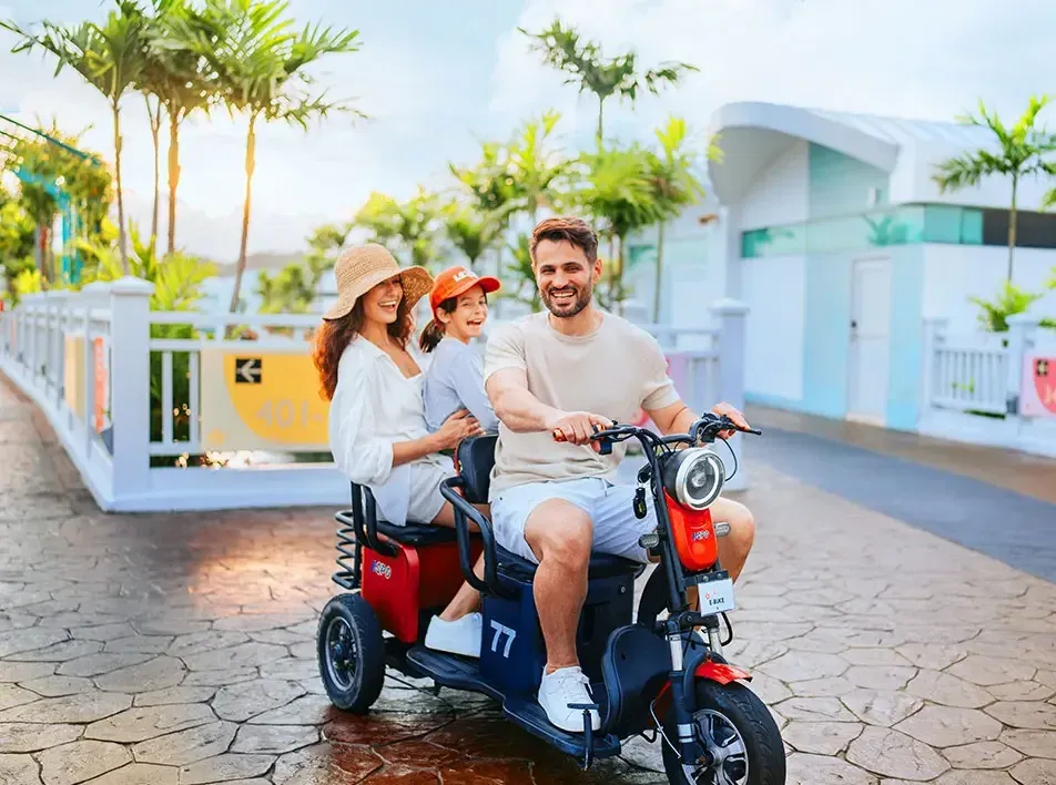 A family enjoying riding an electric bicycle together at the family-friendly resort during their family vacation - Lexis MY