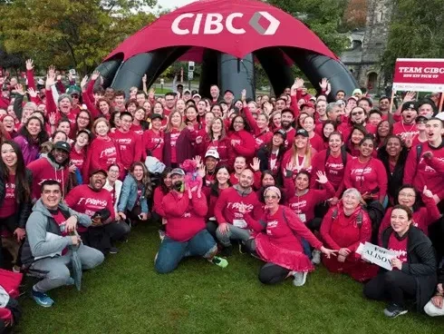 Large group of participants wearing red shirts posing under a CIBC tent outdoors near Jamaica Pegasus Hotel