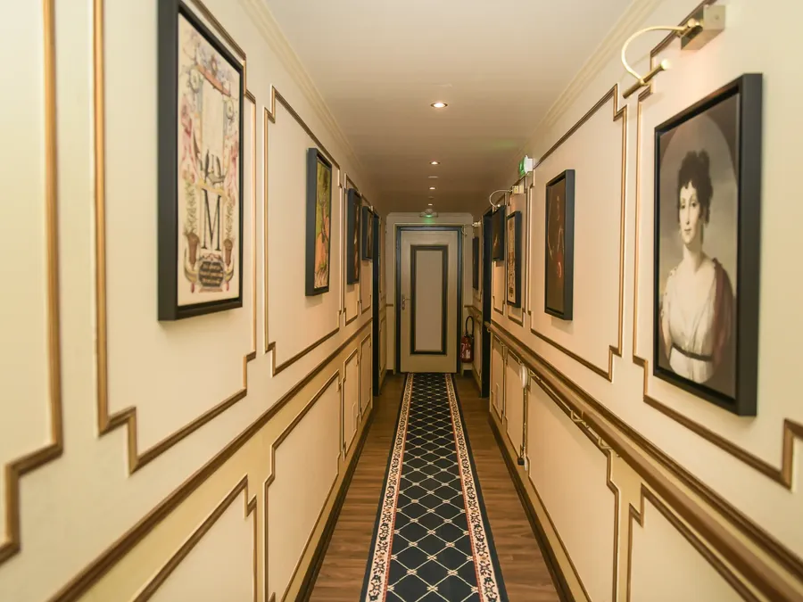 Couloir élégant avec tapis décoratif et cadres dorés à l'Hôtel Villa Aultia.