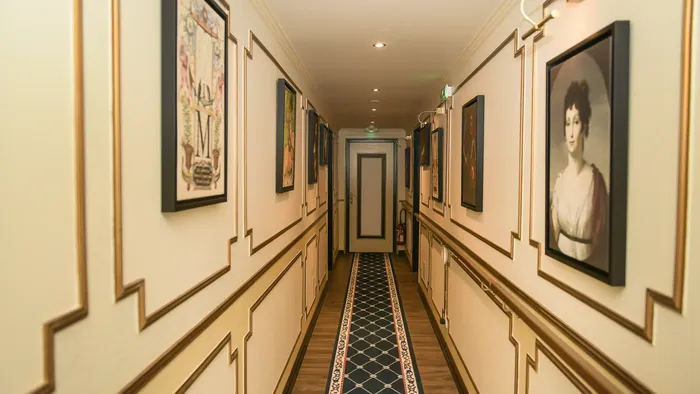 Couloir élégant avec tapis décoratif et cadres dorés à l'Hôtel Villa Aultia.