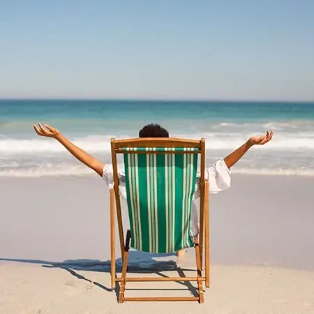 A man sitting on a beach chair, enjoying his relaxing holiday on the beach - Lexis MY