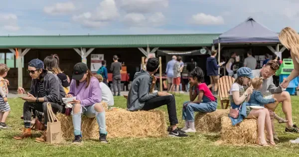 People enjoying their food on hay bails at Clevedon Farmers' Market