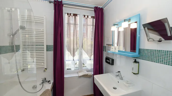 Salle de bain avec baignoire, douche, lavabo, miroir, et fenêtre à l'Hôtel Villa Aultia.