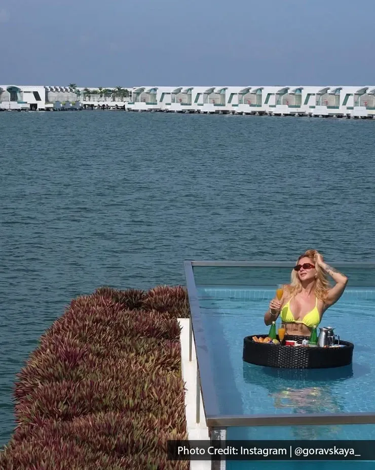 Woman relaxing in an infinity pool with ocean view and floating breakfast tray.