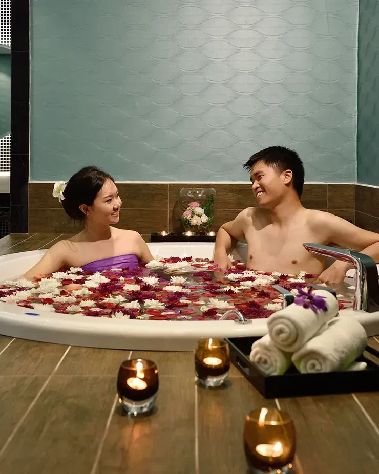 A couple relaxing in a bathtub filled with flower petals in a spa setting - Lexis MY