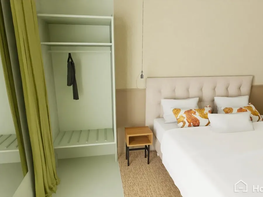 Chambre lumineuse avec lit double capitonné, coussins à motifs floraux et dressing ouvert au Flore Hôtel & Jardin
