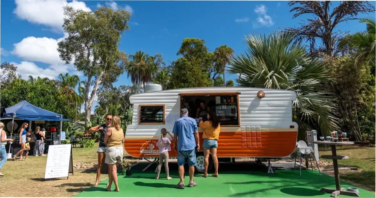 A caravan-style food truck serves customers at a Brisbane market