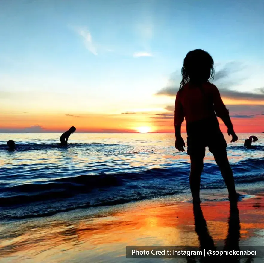 Kids playing at Teluk Kemang Beach during sunset