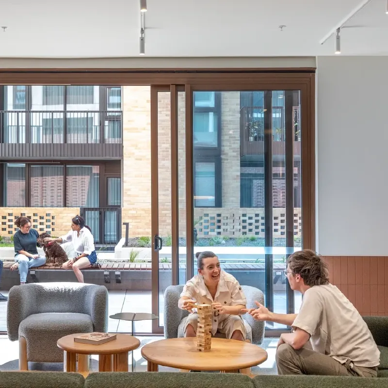 Group of people socializing and playing games in a modern, open-concept lounge area.