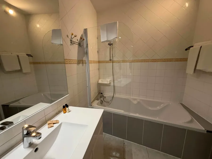 Salle de bains avec baignoire et lavabo de la Chambre confort au Grand Hôtel Molière à Pézenas.