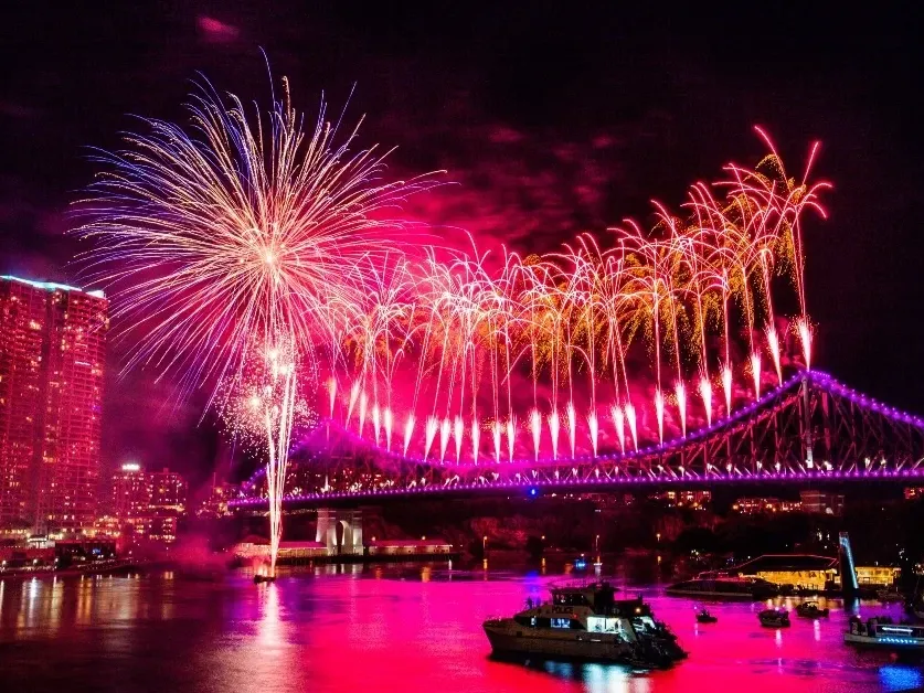Fireworks over a city bridge at night with boats in the water during Riverfire 2026.