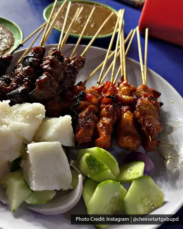 Satay skewers served with cucumber and rice cakes.