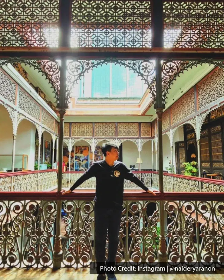 Visitor leaning on railing at Pinang Peranakan Mansion heritage in Penang.