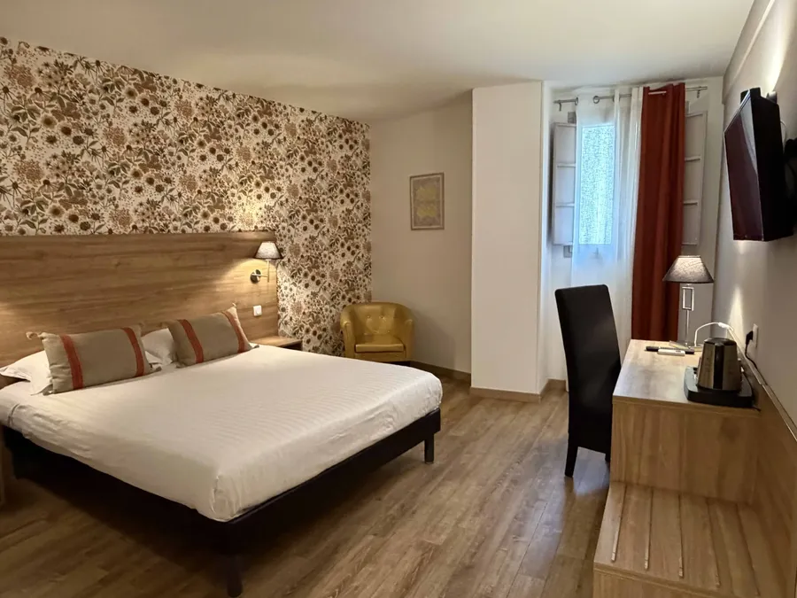 Chambre confort avec lit double et décor floral au Le Grand Hôtel Molière à Pézenas.