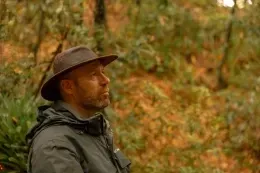 Man wearing a brown hat and dark jacket amid the autumn woodland near Unika Hotels, one of the best hotels in Bogota
