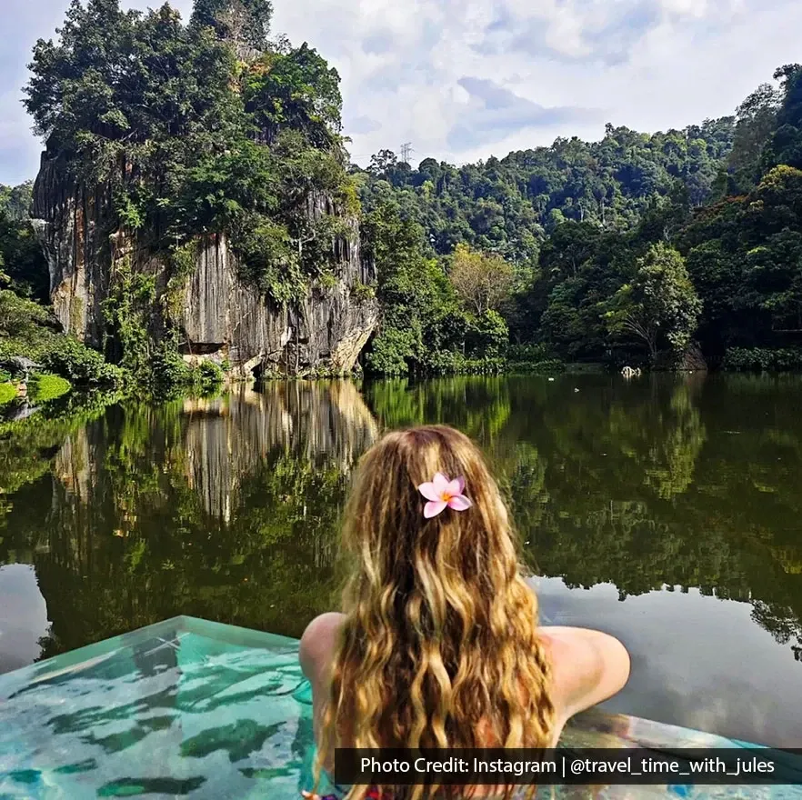 Person relaxing beside lake surrounded by limestone cliffs.
