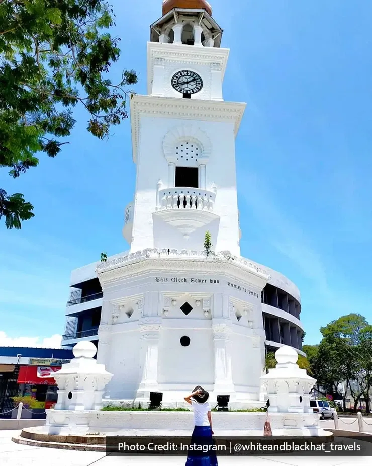 Tourist posing at Queen Victoria Memorial Clock Tower landmark.