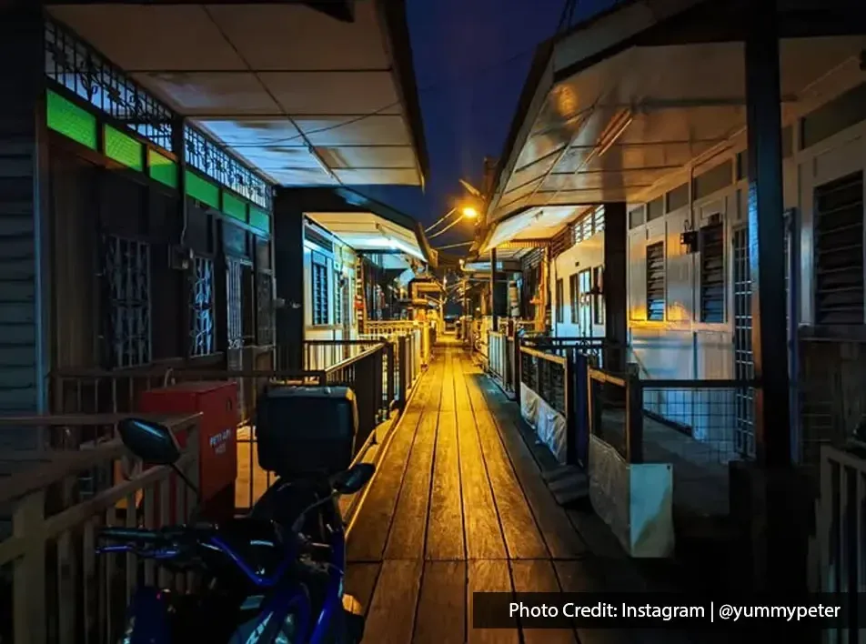 Night view of wooden houses and passageway at Clan Jetty.