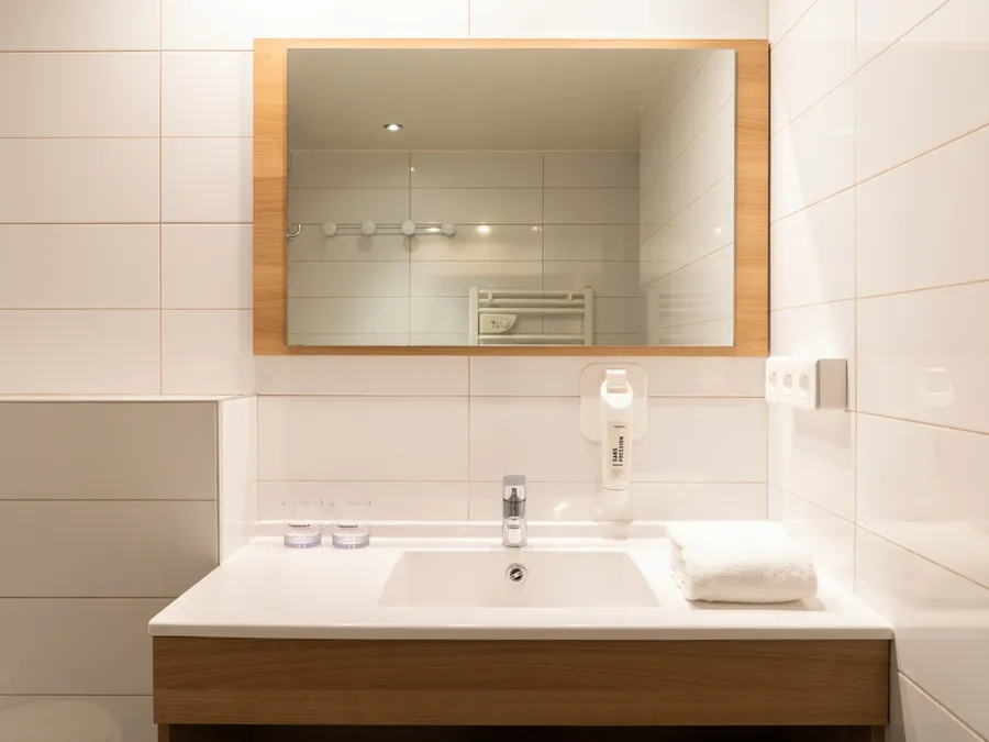 White bathroom sink with mirror and towel at Appart’Hôtel Hévéa, Valence