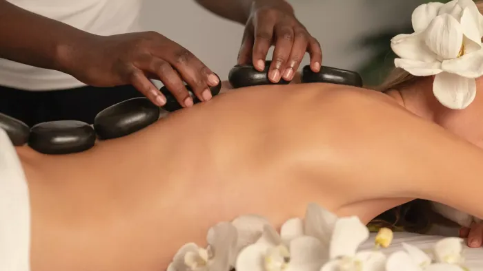 Relaxing hot stone massage therapy with white flowers for guest at the serene Atlantic Hotel & Spa