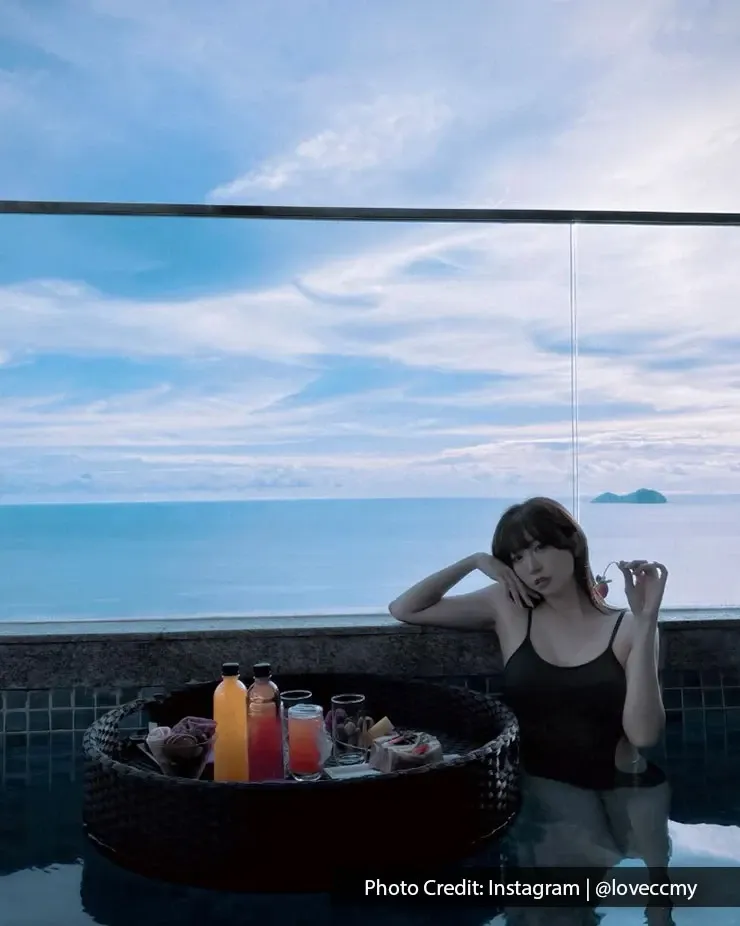 Woman relaxing in private pool with floating breakfast tray at Lexis Suites Penang overlooking the sea