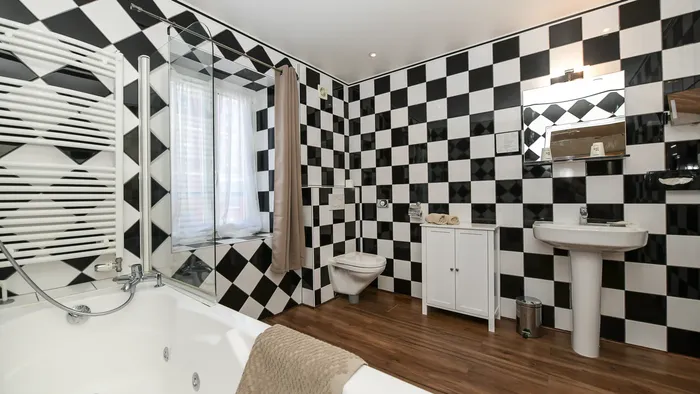 Salle de bains élégante avec baignoire jacuzzi et carrelage damier noir et blanc à Hôtel Villa Aultia