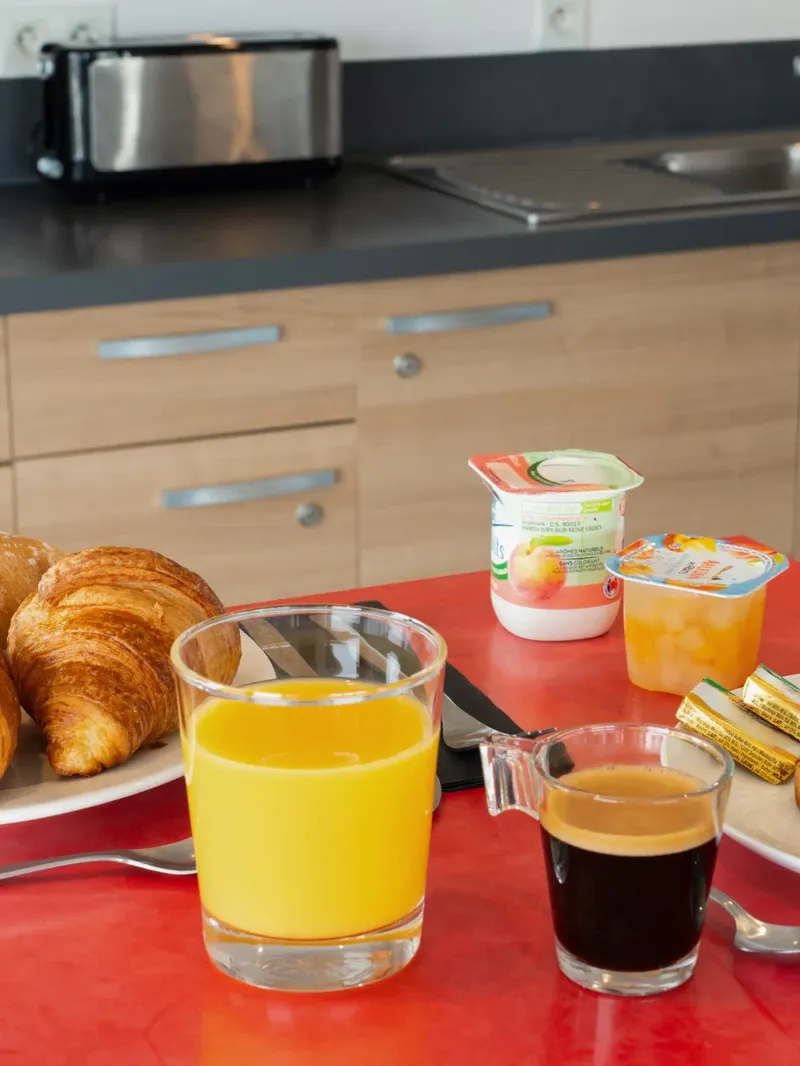 Plates with croissants, orange juice, coffee, and bread at Appart’Hôtel Hévéa in Valence.
