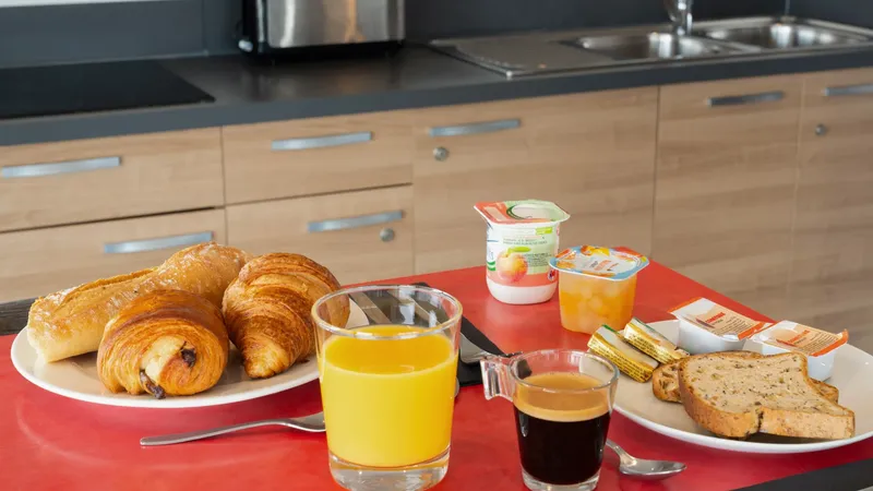 Plates with croissants, orange juice, coffee, and bread at Appart’Hôtel Hévéa in Valence.