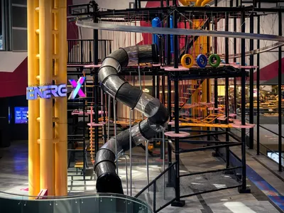 EnerG X Park with a spiral slide and colorful rings in an indoor adventure area.