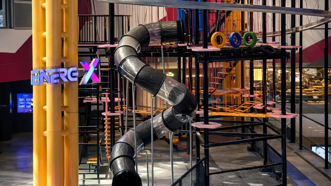 EnerG X Park with a spiral slide and colorful rings in an indoor adventure area.