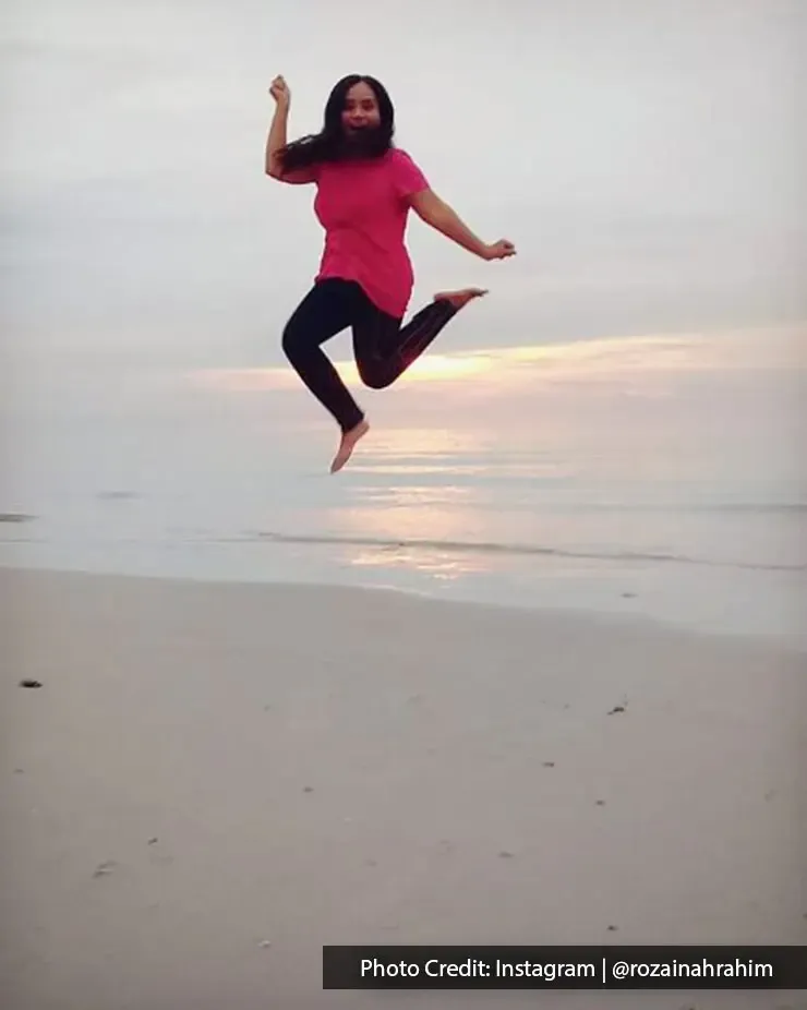 Woman joyfully jumping on the beach during a peaceful sunset - Lexis Hibiscus Port Dickson