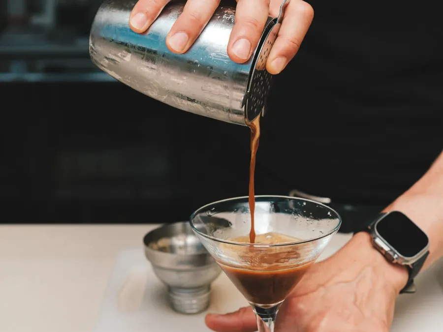 Personne versant un cocktail dans un verre à martini chez Masseria Stali.