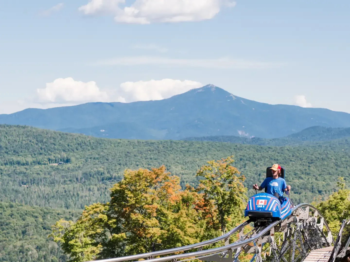 A thrill-seeker rides the mountain coaster with majestic Adirondack mountain views near Lake Placid Club Grandview