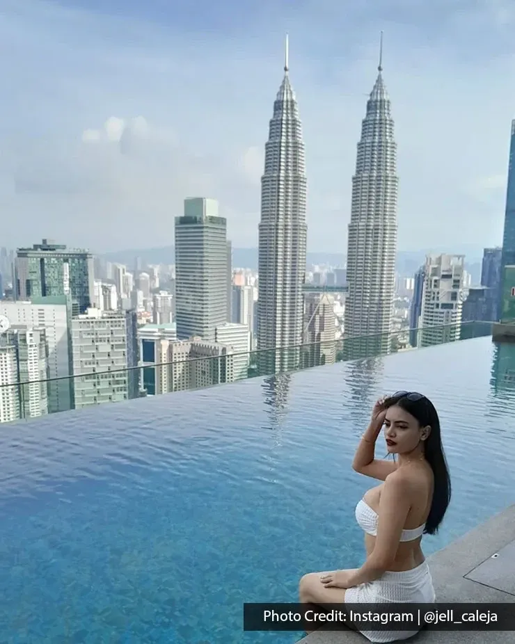 Guest sitting beside an infinity pool overlooking the Petronas Twin Towers