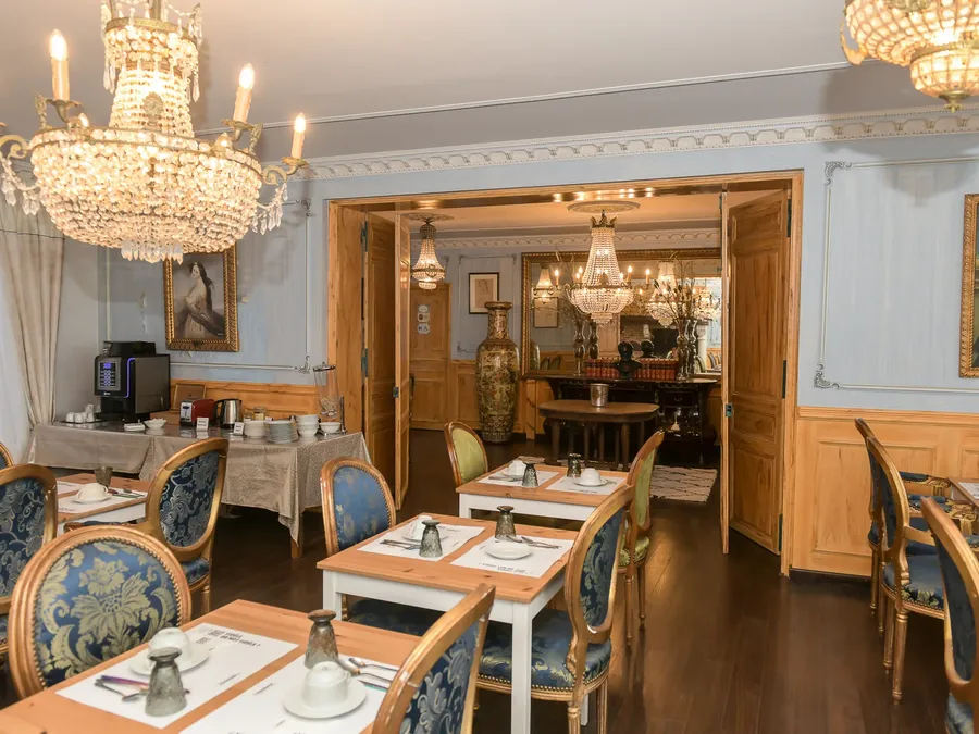 Élégant salon de petit-déjeuner avec tables et chaises, lustres, et portes ouvertes au Hôtel Villa Aultia.